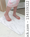 A girl wiping her feet on a diatomaceous earth bath mat 134339122