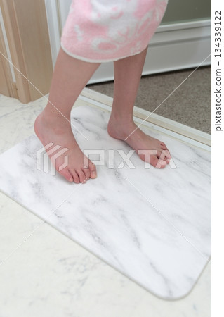 一個女孩正在用矽藻土浴墊擦腳。 134339122