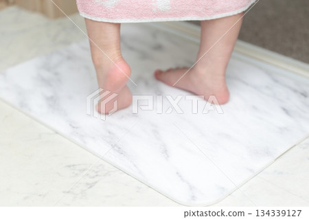 一個女孩正在用矽藻土浴墊擦腳。 134339127