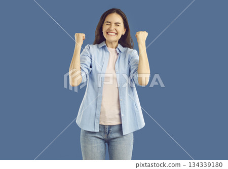 with raised fists. Handsome satisfied man celebrating success, expressing positive emotions over isolated studio background 134339180