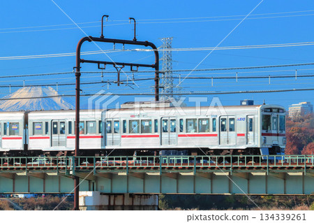 一列塗裝復古風格的7000系列列車駛過多摩川,抬頭望向神聖的富士山。 一列塗裝復古風格的7000系列列車駛過多摩川,抬頭望向神聖的富士山。 134339261