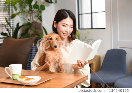 Young Asian woman reading with her dog at home 134340195