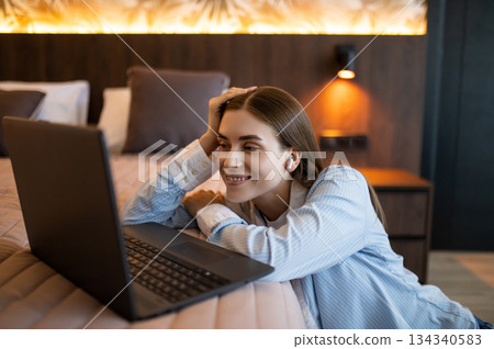 Pretty young woman in a hotel room with a laptop Pretty young woman in a hotel room with a laptop 134340583