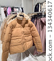 Beige winter puffer jacket with teddy lining hanging on clothing rack in fashion store 134340617
