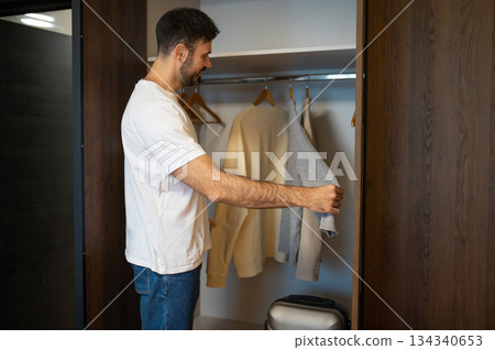 Dark-haired caucasian man checking his clothes in a wardrobe in a hotel 134340653
