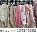 Pastel sweaters and cozy jackets hanging on rack in modern fashion boutique interior 134340692