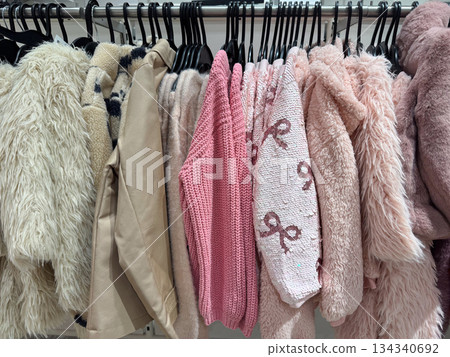 Pastel sweaters and cozy jackets hanging on rack in modern fashion boutique interior Pastel sweaters and cozy jackets hanging on rack in modern fashion boutique interior 134340692