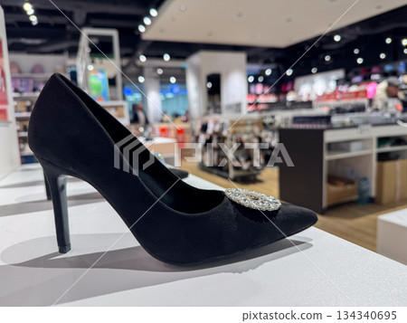 Elegant black high heel shoe with decorative detail displayed in modern fashion store Elegant black high heel shoe with decorative detail displayed in modern fashion store 134340695