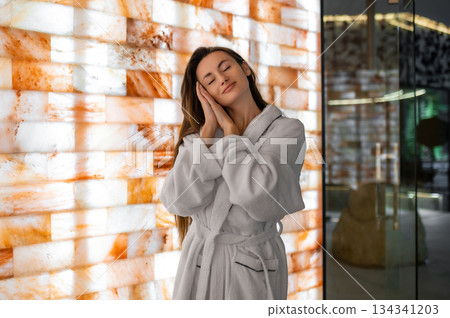 Pretty woman in white bath robe feeling relaxed and peaceful after spa procedures 134341203