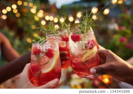 Friends drinking sparkling cocktails. People clinking glasses with drinks outdoors. Close up of hands cheers, making toasts and touch with wineglasses at garden party. Warm Summer Evening. Enjoy Life 134341899