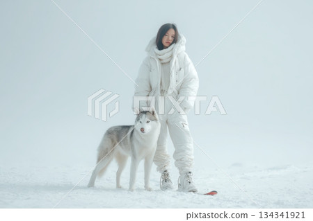Girl makes ski mountaineering with his dog. Woman skiing in snow white mountains with dog. Female snowboarder playing with dog on ski resort, winter sport outdoor. The scene is peaceful and serene Girl makes ski mountaineering with his dog. Woman skiing in snow white mountains with dog. Female snowboarder playing with dog on ski resort, winter sport outdoor. The scene is peaceful and serene 134341921