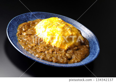 Omelet curry rice photographed against a black background Omelet curry rice photographed against a black background 134342137