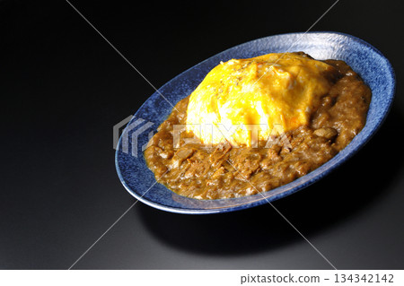 Omelet curry rice photographed against a black background Omelet curry rice photographed against a black background 134342142