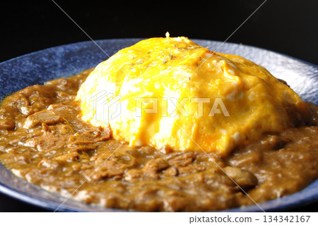 Omelet curry rice photographed against a black background Omelet curry rice photographed against a black background 134342167