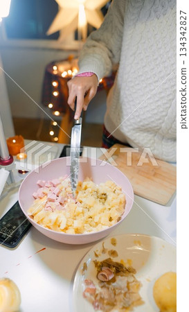 Handcrafting creamy potato mixture with ham and mayonnaise in warm setting 134342827