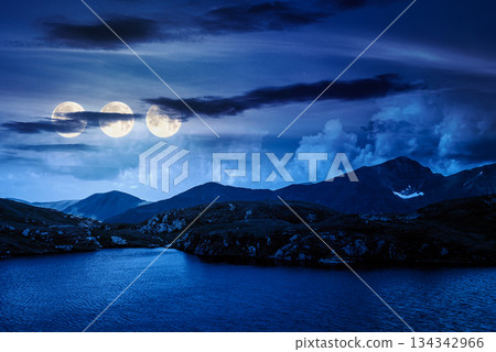 serene alpine lake among green hills at night. beautiful summer landscape with gorgeous sky over mountain peaks in three full moon light. finance bubble investment or abstract concepts serene alpine lake among green hills at night. beautiful summer landscape with gorgeous sky over mountain peaks in three full moon light. finance bubble investment or abstract concepts 134342966
