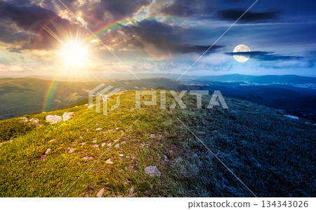 grassy slopes with boulders of mountain. day and night time change concept. beautiful summer solstice scenery in alpine green environment under sky with sun and moon. harmony and progress calendar grassy slopes with boulders of mountain. day and night time change concept. beautiful summer solstice scenery in alpine green environment under sky with sun and moon. harmony and progress calendar 134343026