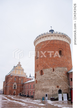 Historic red brick tower stands in a winter scene near old buildings Historic red brick tower stands in a winter scene near old buildings 134343426