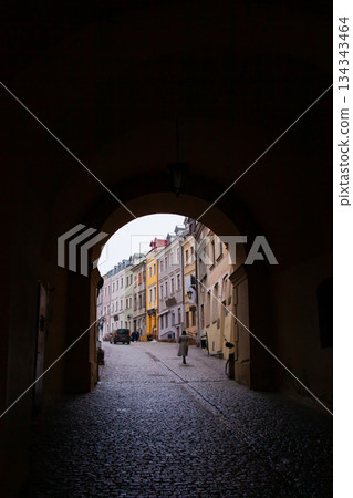Archway leads to narrow street with colorful buildings in the evening Archway leads to narrow street with colorful buildings in the evening 134343464