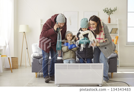 Unhappy family in cold room, dissatisfied parents, children near heater warming the air Unhappy family in cold room, dissatisfied parents, children near heater warming the air 134343483