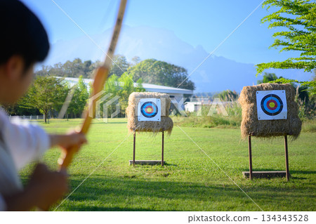 Archer aiming at target in open field 134343528