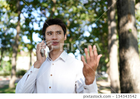 Man talking on phone in park Man talking on phone in park 134343542
