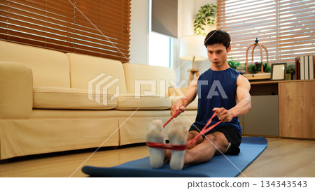 Man exercising with resistance band at home Man exercising with resistance band at home 134343543