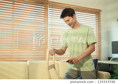 A man assembling new rocking armchair at home with screwdriver, DIY home improvement 134343596