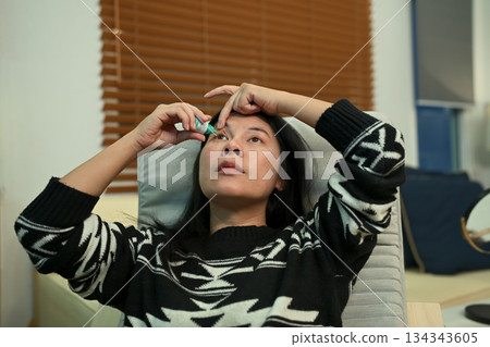 Woman using eyedrops while resting at home Woman using eyedrops while resting at home 134343605
