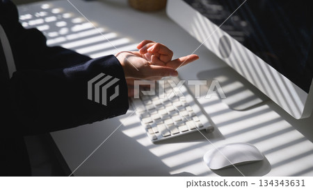 A hand pointing toward the screen above a keyboard with calm light and shadow on the desk A hand pointing toward the screen above a keyboard with calm light and shadow on the desk 134343631