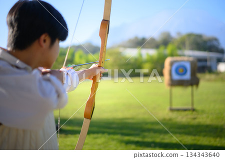 Archer aiming at target in open field Archer aiming at target in open field 134343640