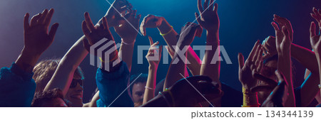 Group of young people dancing closely at night event. Banner 134344139