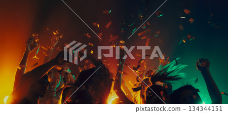 Dancing crowd with confetti under dramatic club lighting. Dancing crowd with confetti under dramatic club lighting. 134344151