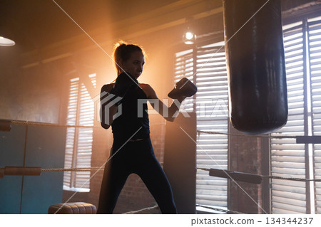 Women self defense girl power. Strong woman fighter training punches on boxing ring. Healthy strong girl punching boxing bag. Training day in boxing gym. Strength fit body workout training Women self defense girl power. Strong woman fighter training punches on boxing ring. Healthy strong girl punching boxing bag. Training day in boxing gym. Strength fit body workout training 134344237