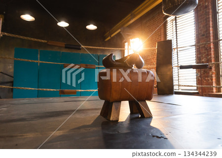 Boxing gloves lying down on boxing ring in empty gym. Equipment for fight training competition black protective boxing gloves ready for fighter winner on ring. Strength fit body workout training 134344239