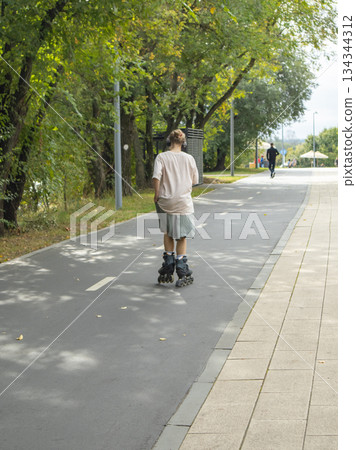 Person rollerblading on a park path active leisure vertical Person rollerblading on a park path active leisure vertical 134344312