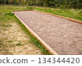 Outdoor petanque bocce court with gravel surface and wooden borders in park 134344420