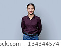 Portrait of beautiful smiling young woman posing on gray studio background 134344574