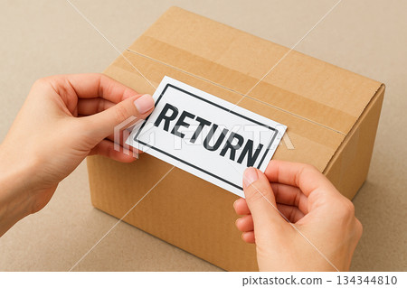 Female hand holding return label on cardboard box 134344810