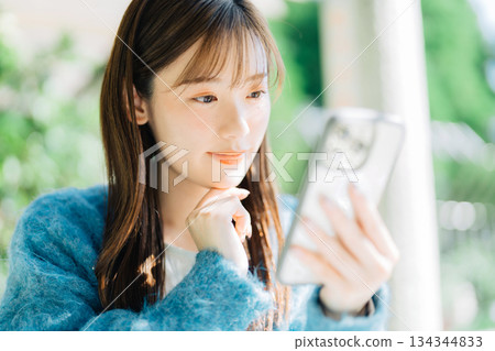 Woman looking at smartphone on terrace 134344833
