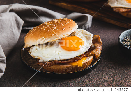 A delicious burger with a fried egg, bacon and cheese on a plate on the table 134345277