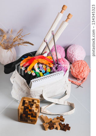 Analog bag of yarn, markers, a notebook, needles, and puzzles for a digital detox vertical view Analog bag of yarn, markers, a notebook, needles, and puzzles for a digital detox vertical view 134345323