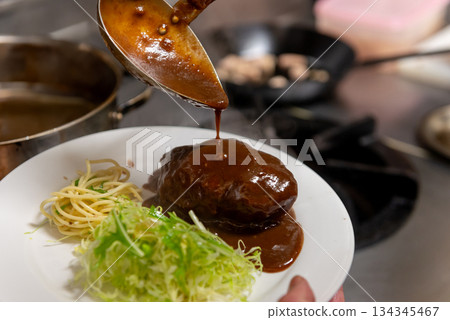 Hamburger steak cooking scene with demi-glace sauce 134345467
