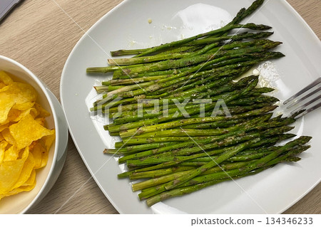 Roasted Asparagus and Crispy Potato Chips on a Wooden Table Roasted Asparagus and Crispy Potato Chips on a Wooden Table 134346233