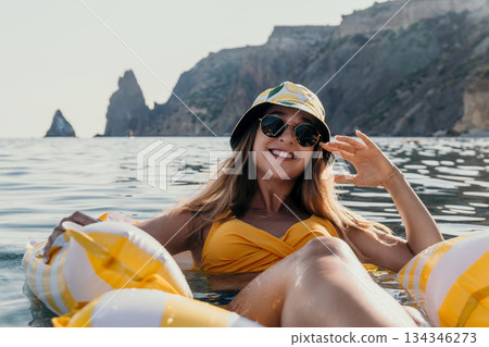 Woman Beach Float Summer - Smiling woman relaxing on a yellow float in the sea on a sunny day. Woman Beach Float Summer - Smiling woman relaxing on a yellow float in the sea on a sunny day. 134346273
