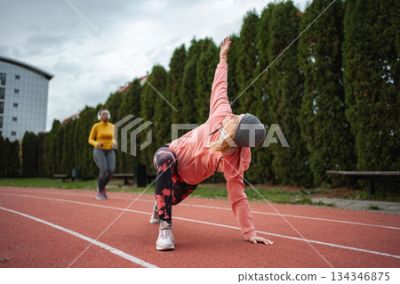 Two mid adult women exercising on a running track 134346875