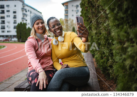 Friends smiling, taking selfie after workout on sports field 134346879