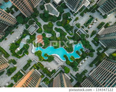 Aerial view of modern residential area featuring greenery, water features, and recreational spaces in urban setting. 134347122