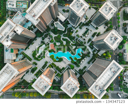 Aerial view of modern residential area featuring greenery, water features, and recreational spaces in urban setting. 134347123