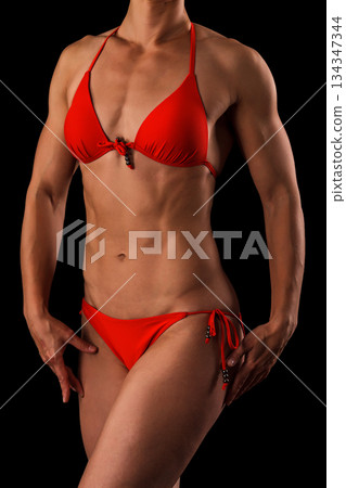 Muscular female body against black background. Muscular female body against black background. 134347344